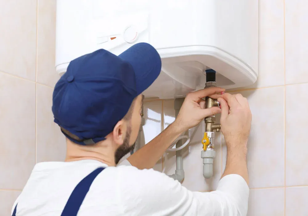 Plumber installing or repairing tankless water heater in Utah home bathroom
