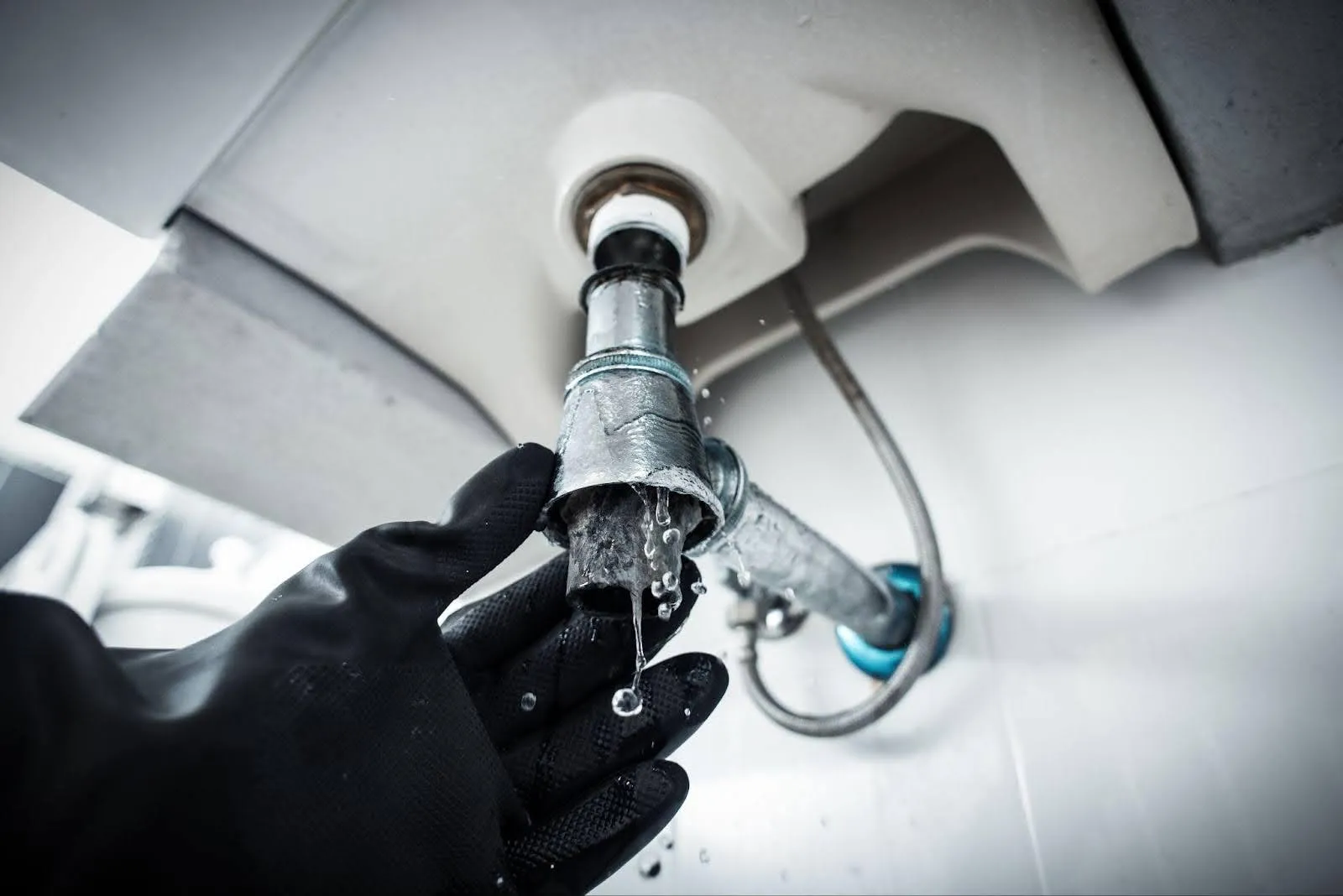 A gloved individual is grasping a faucet, showcasing attention to detail in plumbing tasks