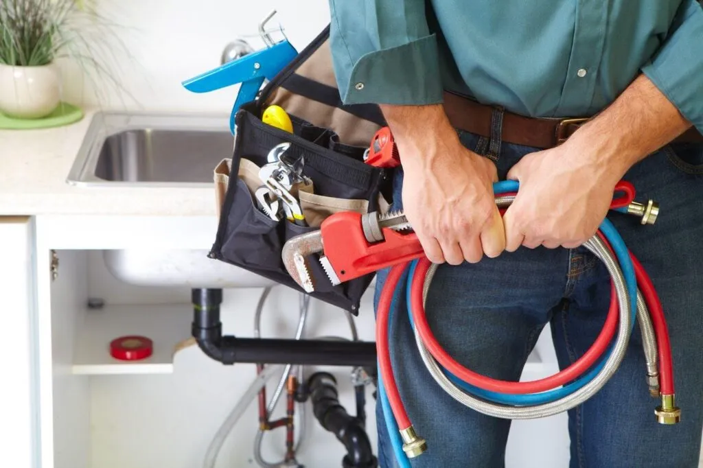 A man grips a hose and tools prepared for outdoor work or gardening activities