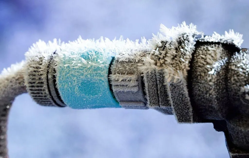 Close-up of a frosted water pipe showcasing intricate ice patterns on its surface