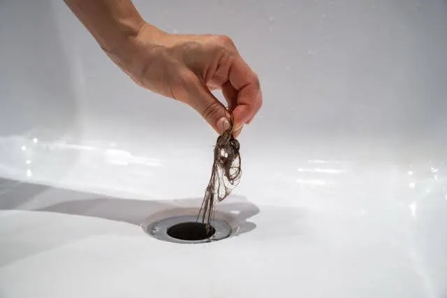 A person holds a piece of metal over a sink preparing to clean or inspect it